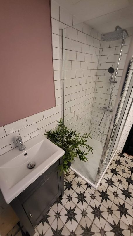 Modern bathroom with pink walls and black & white tiles, creating a stylish look.